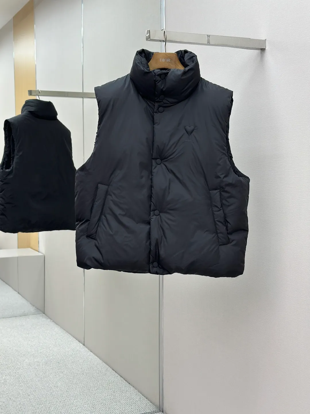 P810 AMIPARIS love padded embroidered down vest Fabric selection: Taffeta fabric woven from 100% polyester fiber. It adopts warp and weft plain weave and is woven very tightly, making the surface of the fabric extremely smooth and flat, with a "skinny" and stiffness that is not easy to collapse. When rubbed or moved around, it will make a unique, crisp "rustling" sound. At the same time, it has a delicate plain texture and a soft, elegant silky luster. This kind of luster is not as dazzling as satin, but more restrained and advanced.  Lining selection: Use 100% nylon to create the lining. The high-density and tight weaving process prevents tiny lint from getting out of the gaps in the fabric. The smooth surface improves the putting on and taking off experience, and the excellent wear and tear resistance ensures damage caused by frequent use, while the light and soft texture does not affect the overall weight.  Technology: The fabric and padding material are tightly fixed on the frame of the embroidery machine. The embroidery machine uses sparse stitches along the padding layer to outline the filling area of the pattern, and then runs the overlay layer's padding, using dense stitches to perfectly cover the foam padding layer, thus forming a slightly raised love embroidery, which feels soft and full, enhancing recognition while maintaining a low profile. High-quality filling: It uses 90 white duck down with a weight of 160g to ensure excellent thermal insulation performance. After strict screening and processing, the velvet is not easy to get drilled, ensuring durability.  Accessories: One-to-one customized three-standard, one-to-one customized hem elastic buckle, one-to-one customized snap button SIZE: XS S M L